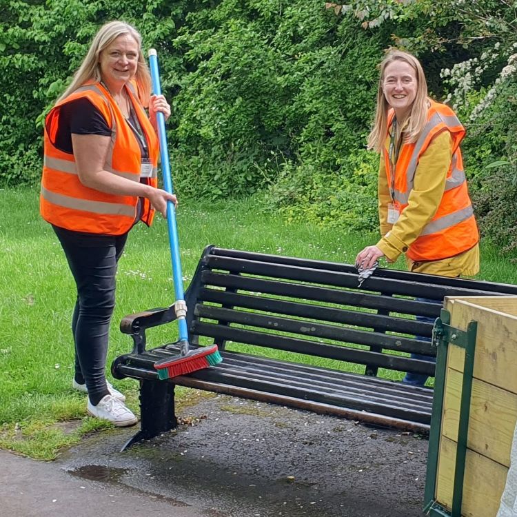 Two people out in the community cleaning a park area