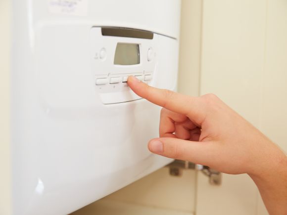 A hand pressing a button on a domestic boiler