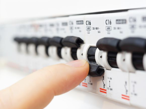 Finger on a tripped fuse in a fuse box.