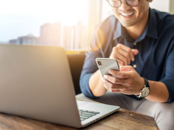 Man on laptop with smartphone