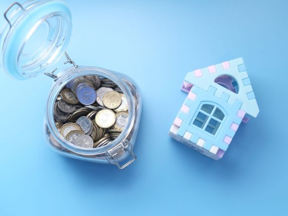 A jar of coins next to a model house