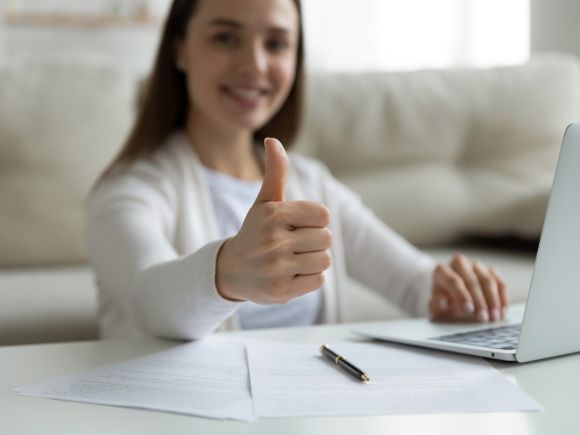 Woman working on a laptop showing 'Thumbs Up'