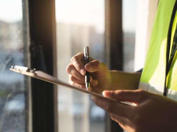 An inspector checking a property and taking notes on a clipboard to review and fix the home.