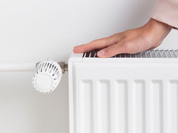 Person checking a radiator by putting their hand on the top to test for heat