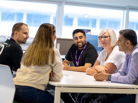 Group of staff having a happy conversation around a table