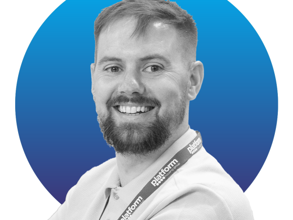 Black and white image of a man in a white shirt sat in front of a blue circle