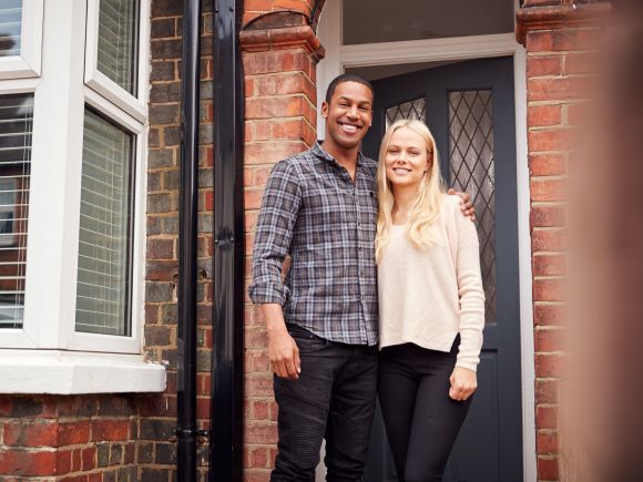 Happy young couple, Man and Woman stood on the doorstep of their house