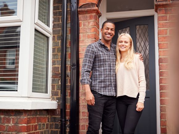 Happy young couple, Man and Woman stood on the doorstep of their house