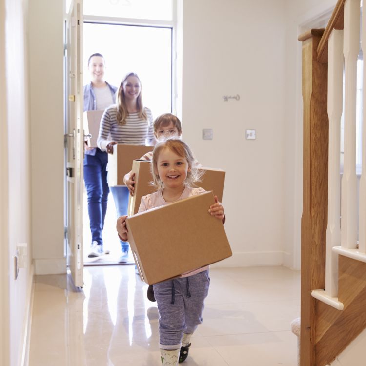 Family carrying boxes into new home