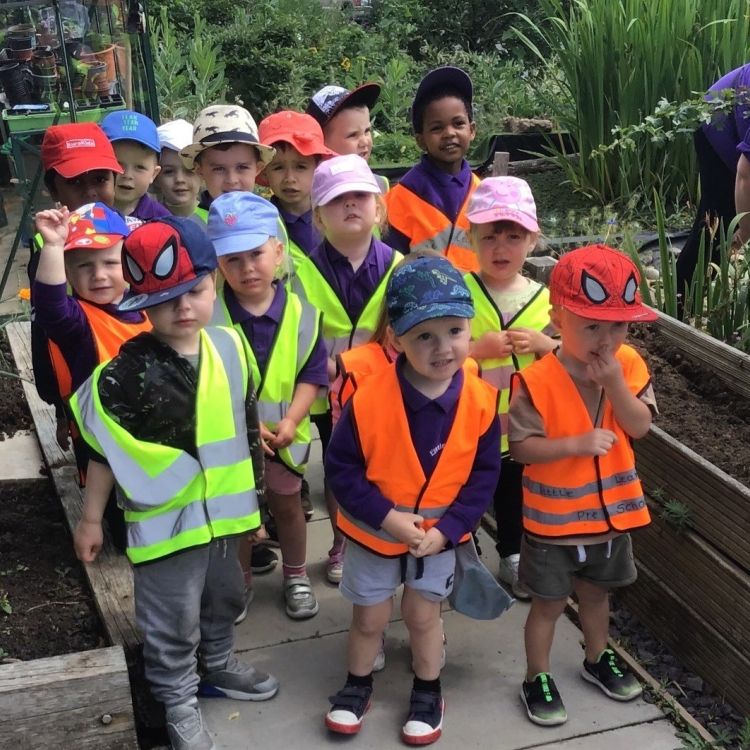 A group of young children in high-vis vests gardening