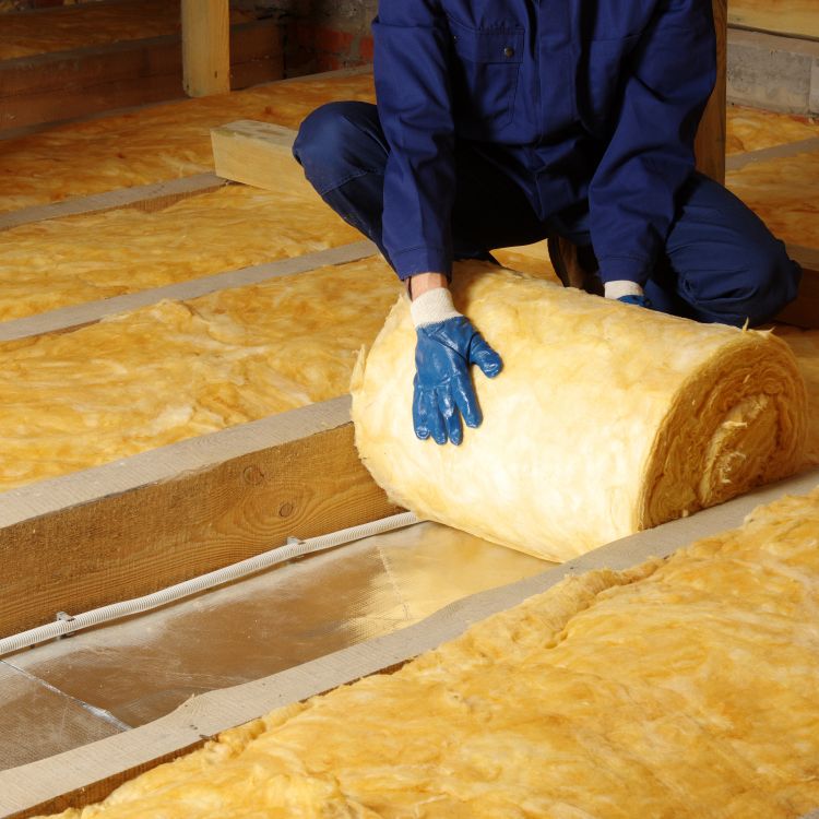 man laying loft insulation in loft space