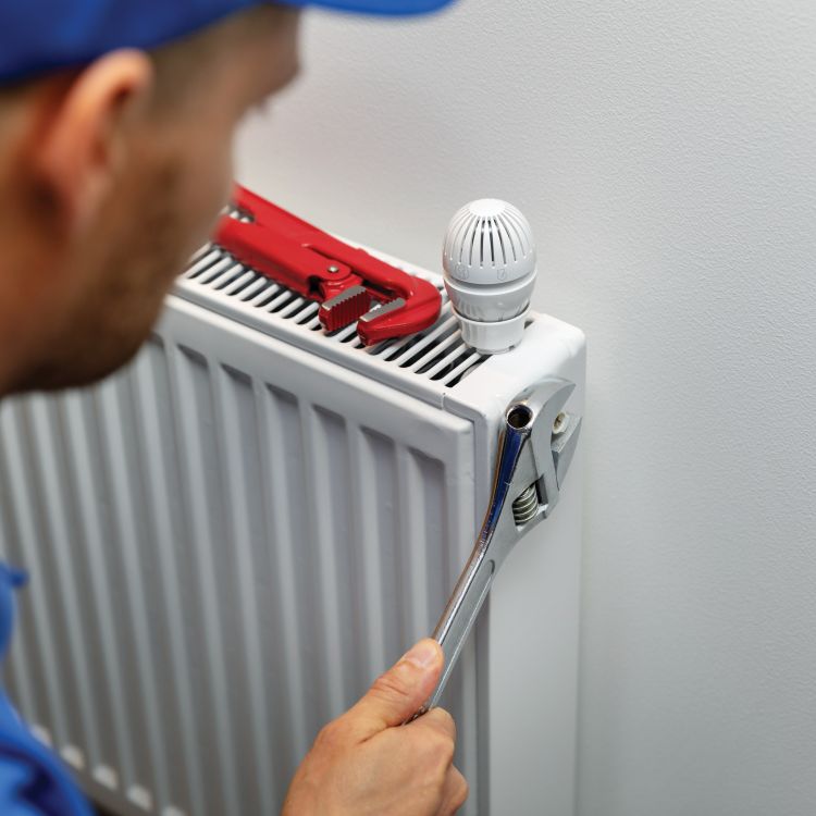 Man fixing a radiator with a spanner