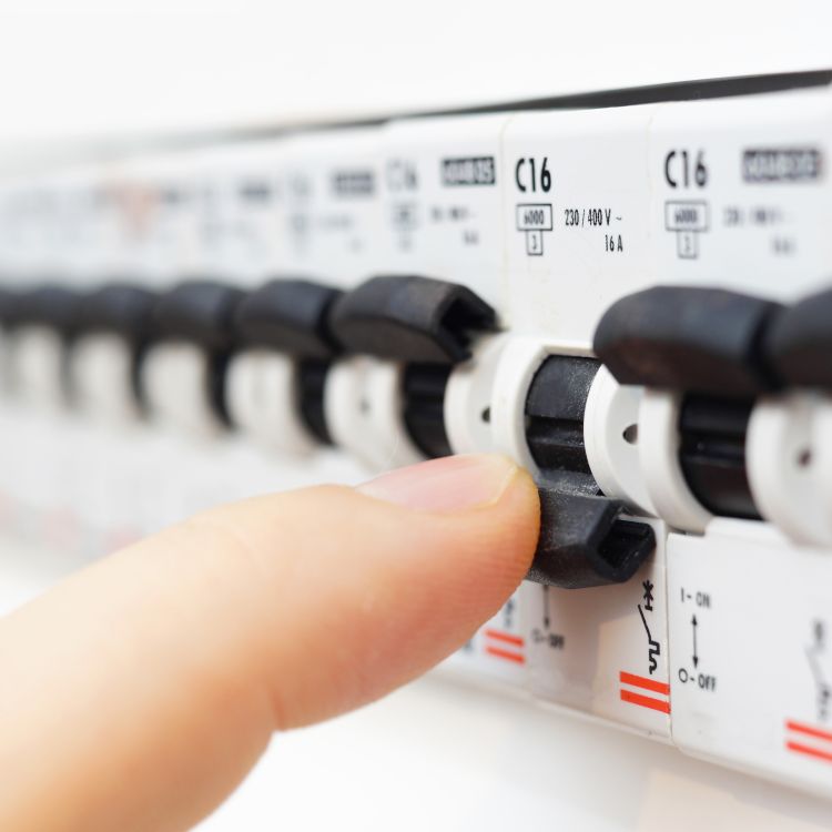 Finger on a tripped fuse in a fuse box.