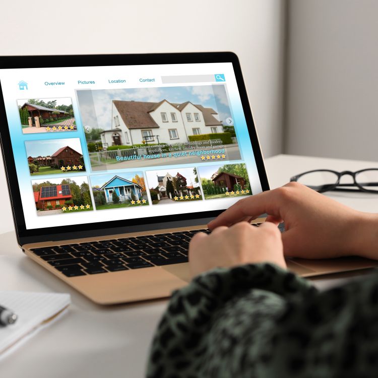 Close up view of a woman looking at properties on a housing website via laptop at table