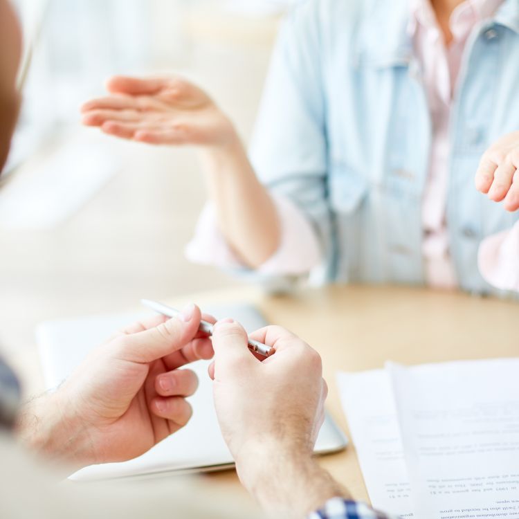 Two people listening to a housing professional explaining documents.