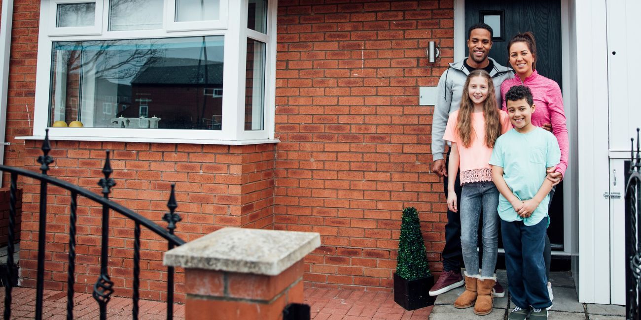 Happy family standing on the doorstep of their home