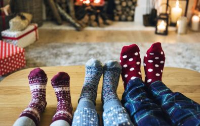 Image of family feet in thick socks resting on a table in front of a fire as they are all prepared for winter