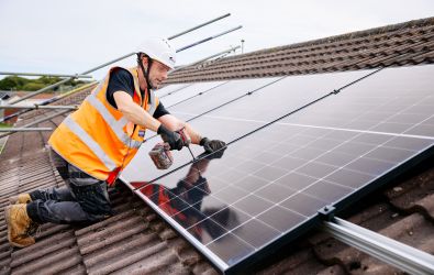 An installer fitting a solar panel on a roof