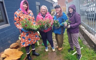 Communities Connected volunteers holding pots of flowers